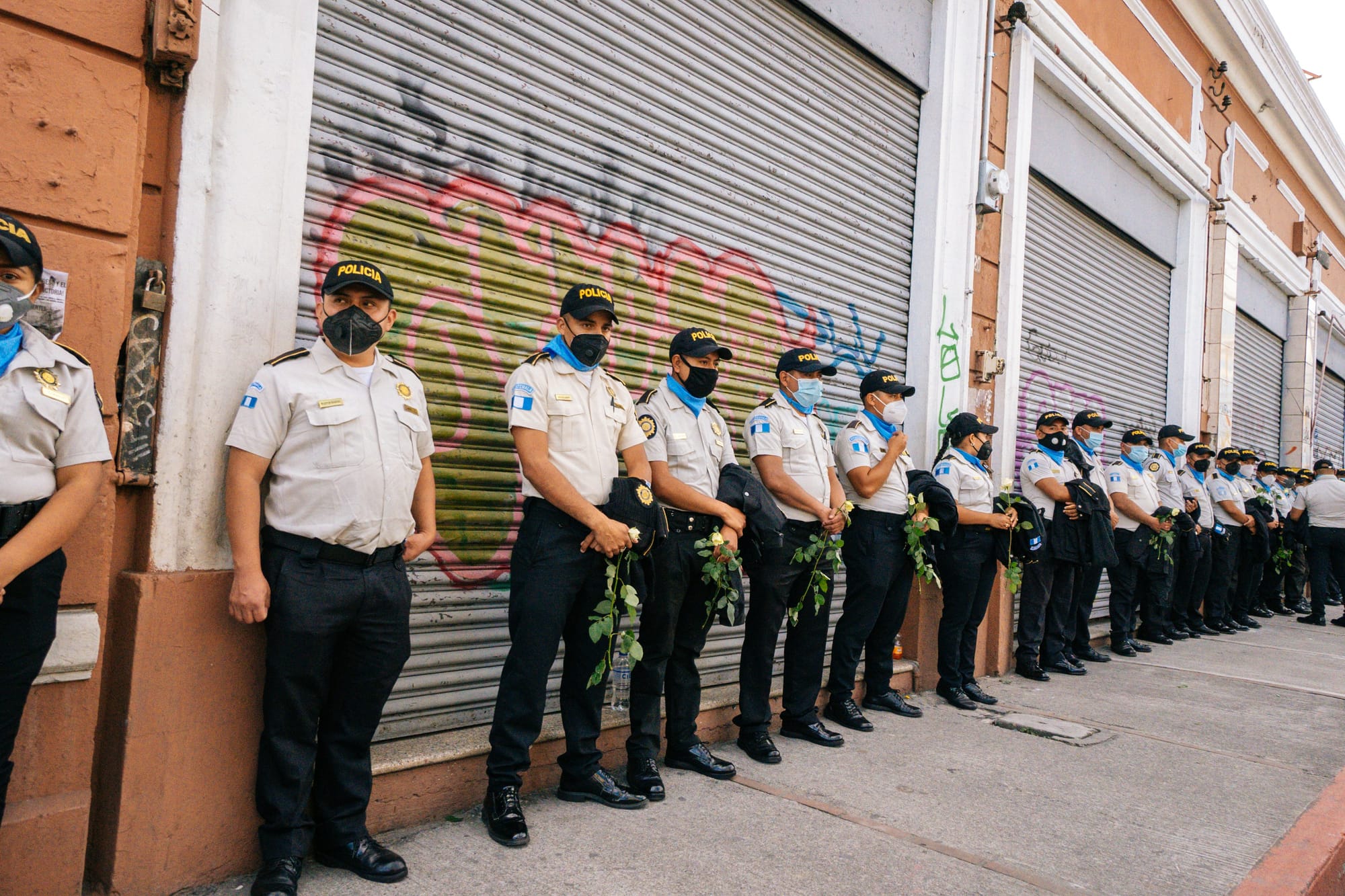 A line of police officers going down the sidewalk next to a building